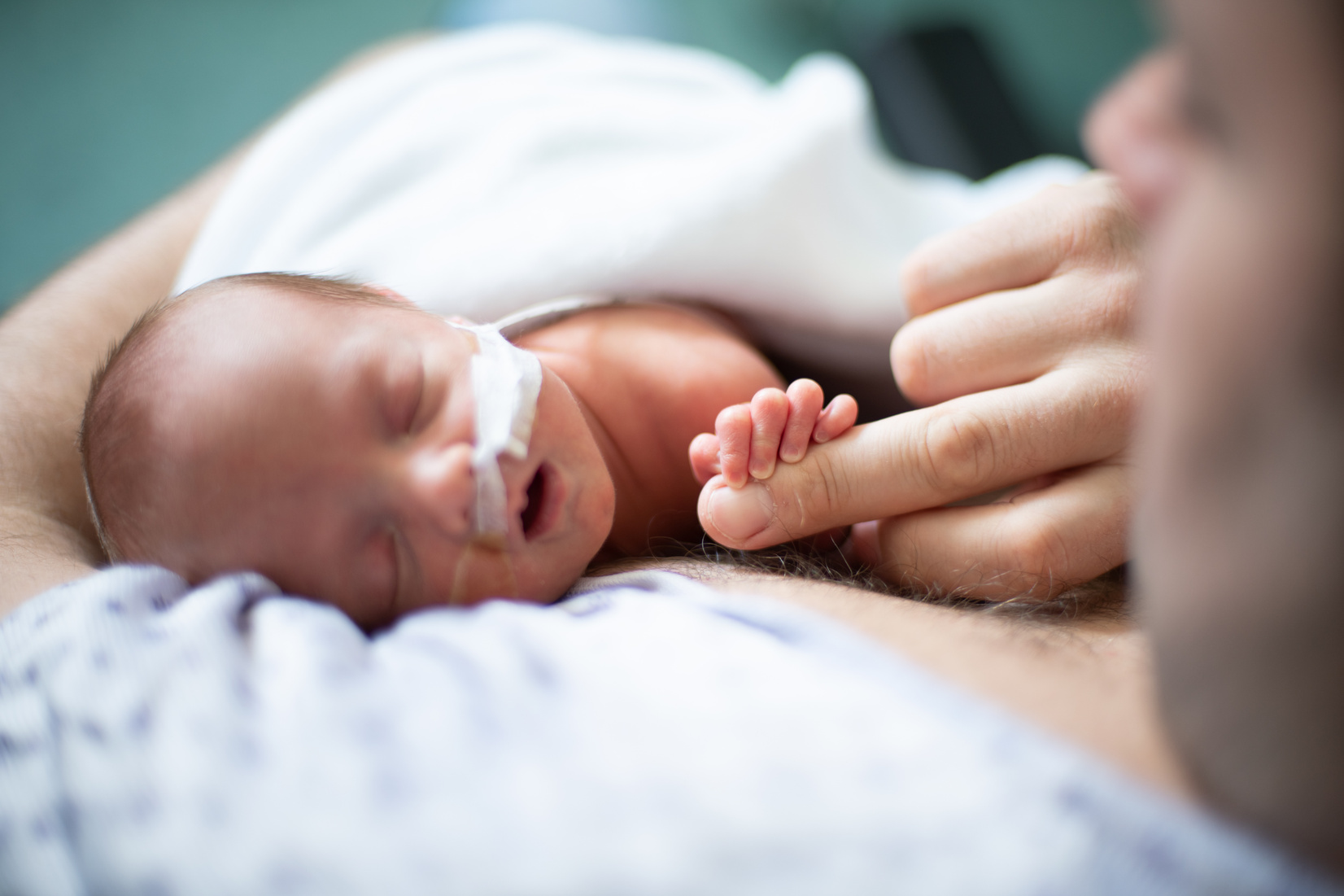 Father taking care of his premature baby doing skin to skin at hospital